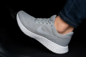 پای راننده روی پدال خودرو با کتونی ورزشی مناسب رانندگی در نور طبیعی و فضای واقعی.